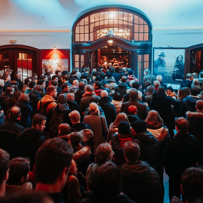 Foule attendant dans le hall d&rsquo;un cin&eacute;ma pour participer &agrave; un &eacute;v&eacute;nement cin&eacute;matographique populaire.
