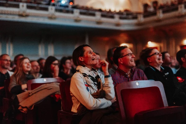 Lachend publiek in een zaal, geboeid door een vermakelijk filmevenement.